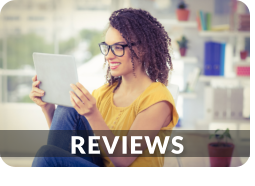 A young woman is smiling while looking at a tablet that is propped on her knee. This link goes to the Murphy Wainer reviews page.