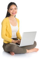 Young woman sits cross-legged on the floor with a laptop open in her lap, her fingers on the keyboard. She is looking at the camera and smiling.
