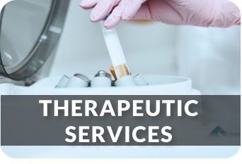 A medical technician wearing gloves removes a tube from a centrifuge machine. The image links to the Therapeutic Services page.