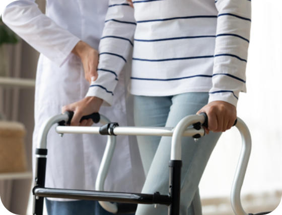 A medical professional assists a young woman in using a walker.
