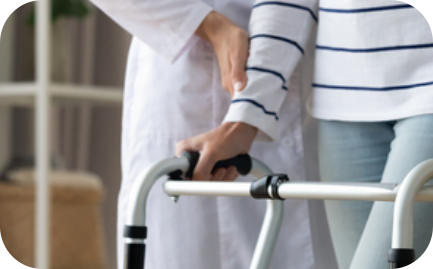 A medical professional assists a young woman in using a walker.