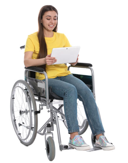 A young woman wearing jeans and a tshirt is sitting in a wheelchair looking at a tablet she is holding in her hands.