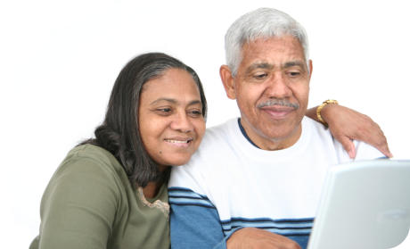 A senior man and woman are sitting together looking at a computer screen.