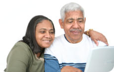 A senior man and woman are sitting together looking at a computer screen.