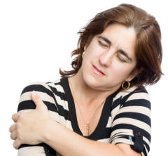 A person is grimacing and holding their shoulder in pain.