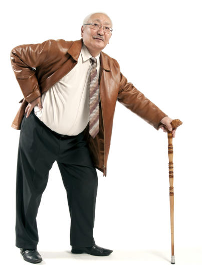 An elderly man in a suit is holding his hip and leaning on a cane.