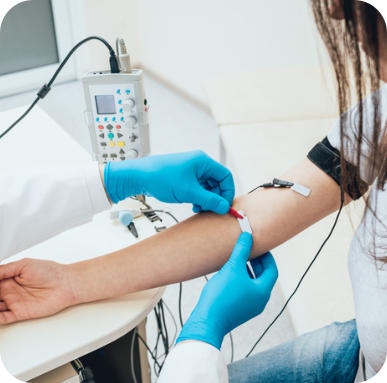 A technician wearing gloves attaches EMG sensors to the arm of a patient. 