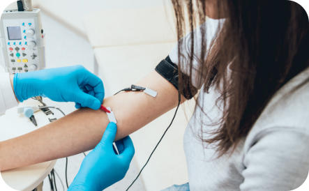 A technician wearing gloves attaches EMG sensors to the arm of a patient. 