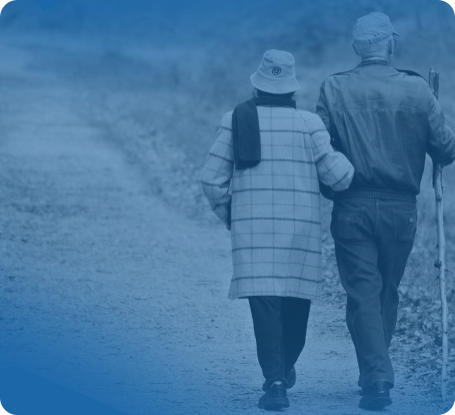 An elderly couple is dressed in warm clothing and walking arm in arm down a path. The man is holding a walking stick. The image is a background for the patient review displayed on the page.